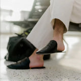 Man in white pants wearing black leather slippers at airport waiting area