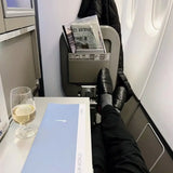Business class airplane seat with legs up, Club World menu, wine glass, and newspaper