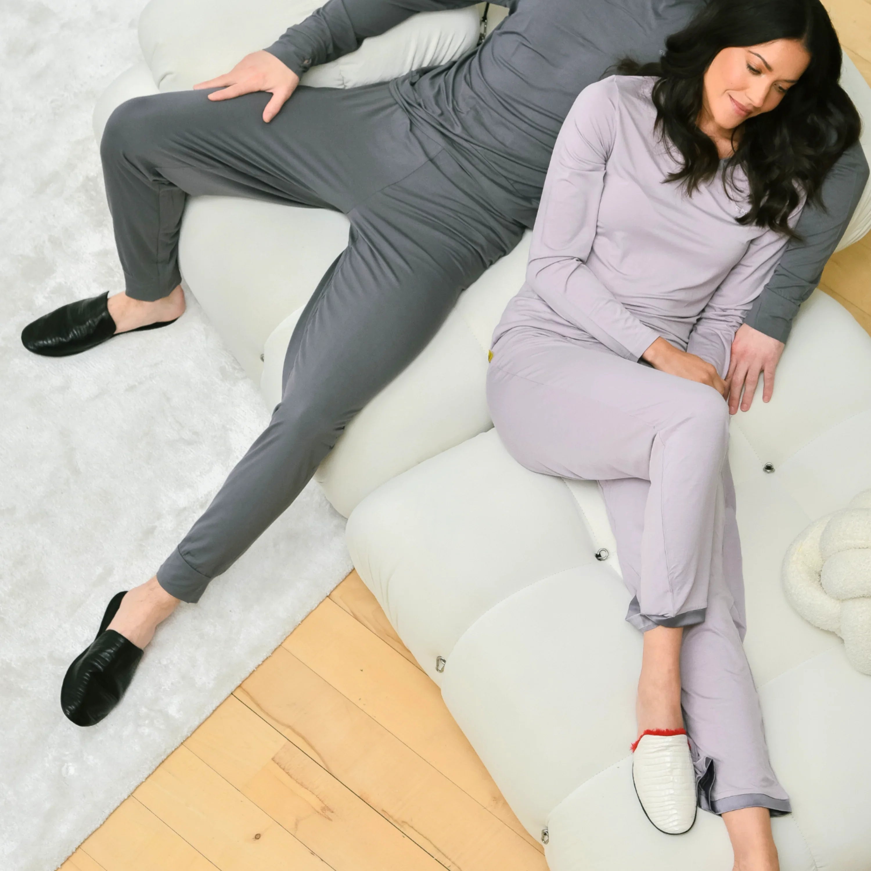 Couple lounging on sofa in matching pajamas and slippers, cozy home loungewear setting