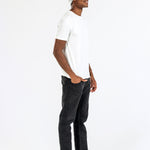 Man wearing grey cashmere hat, white t-shirt, black jeans, loafers on white background