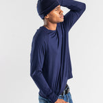 Man wearing navy cashmere hat and long sleeve shirt with jeans on white background