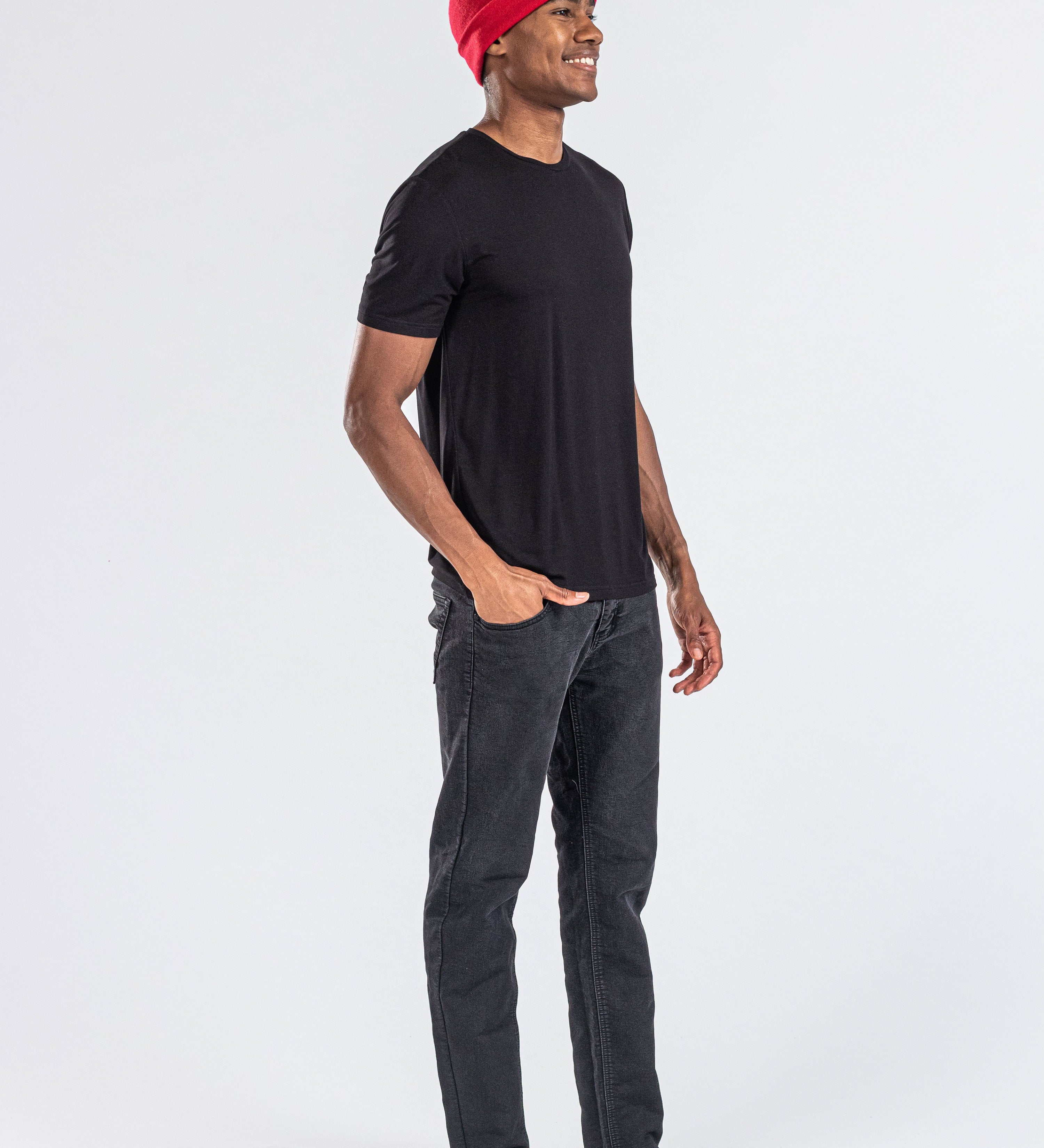 Man wearing a red cashmere hat, black t-shirt, and black jeans on white background