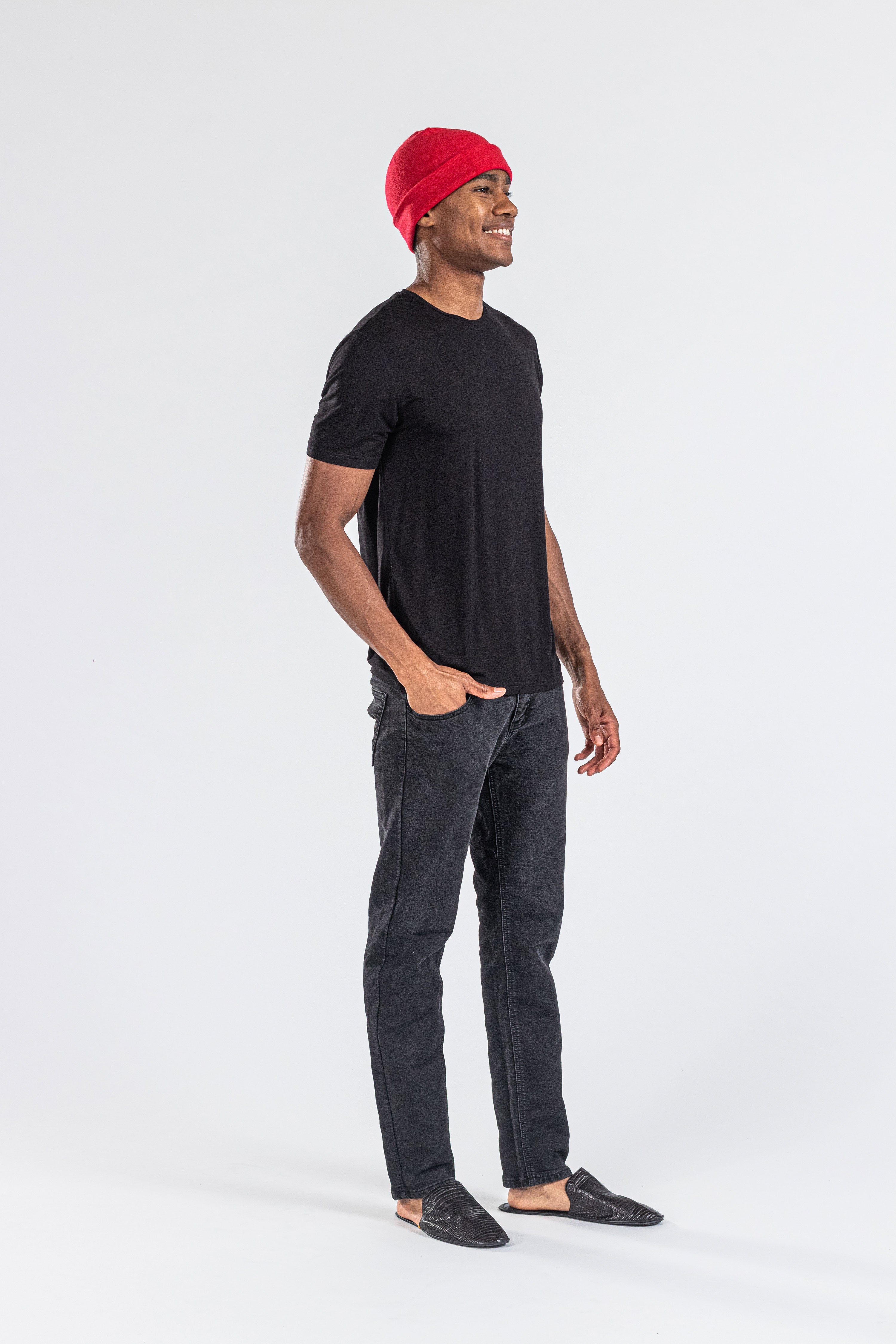 Man wearing a red cashmere hat, black t-shirt, and black jeans on white background