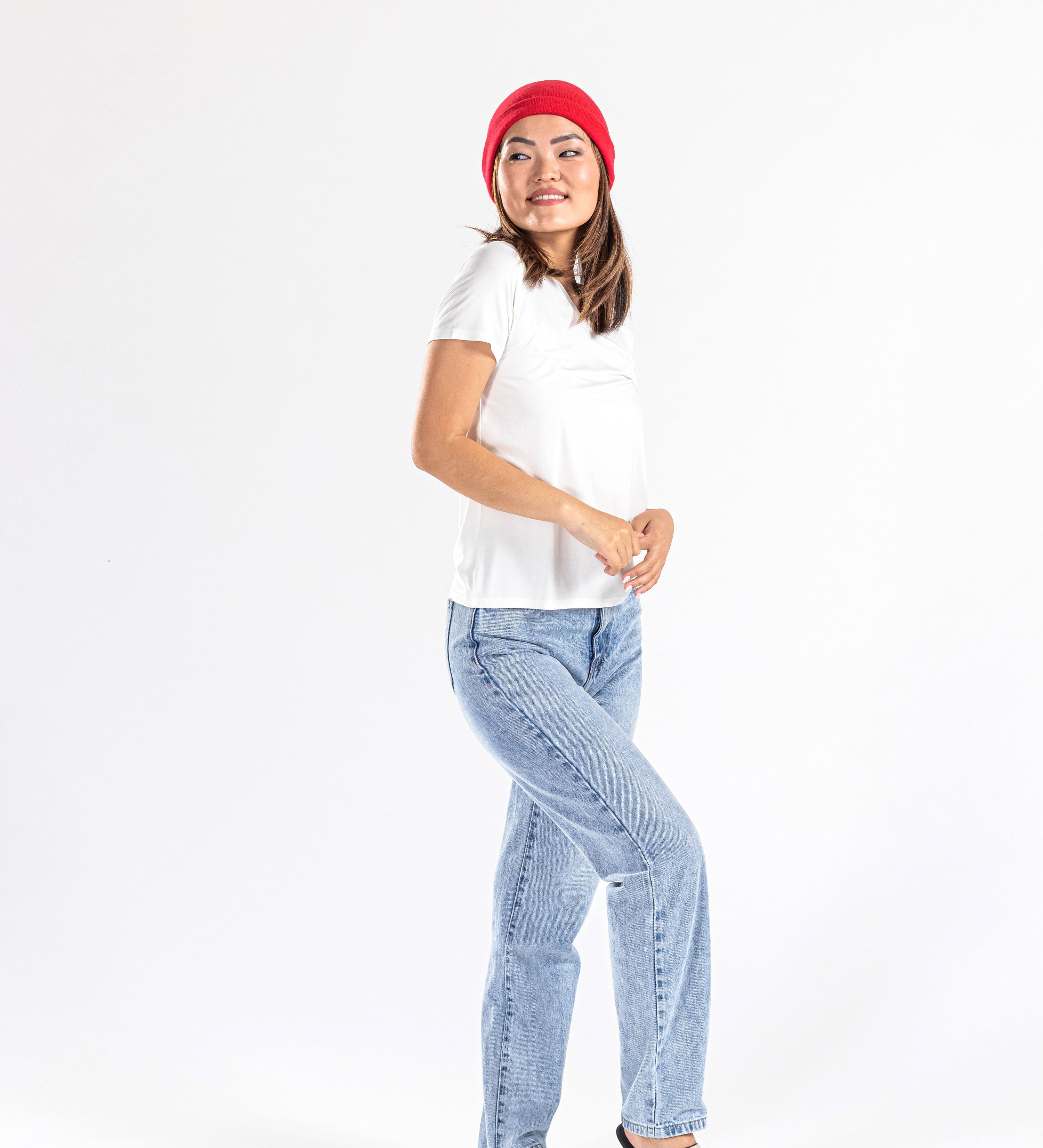 Woman wearing red cashmere hat, white t-shirt, and light blue jeans on white background
