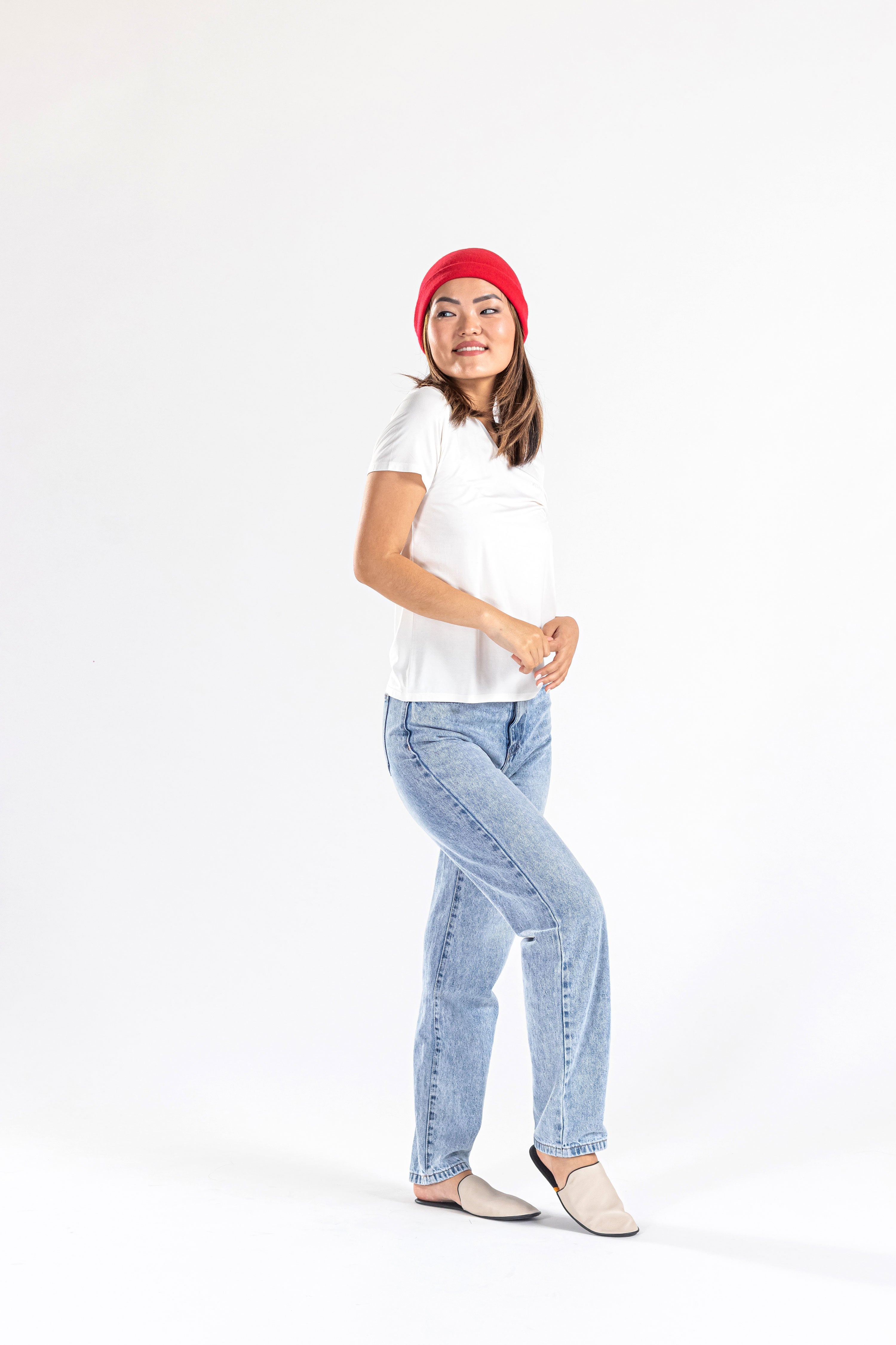 Woman wearing red cashmere hat, white t-shirt, and light blue jeans on white background