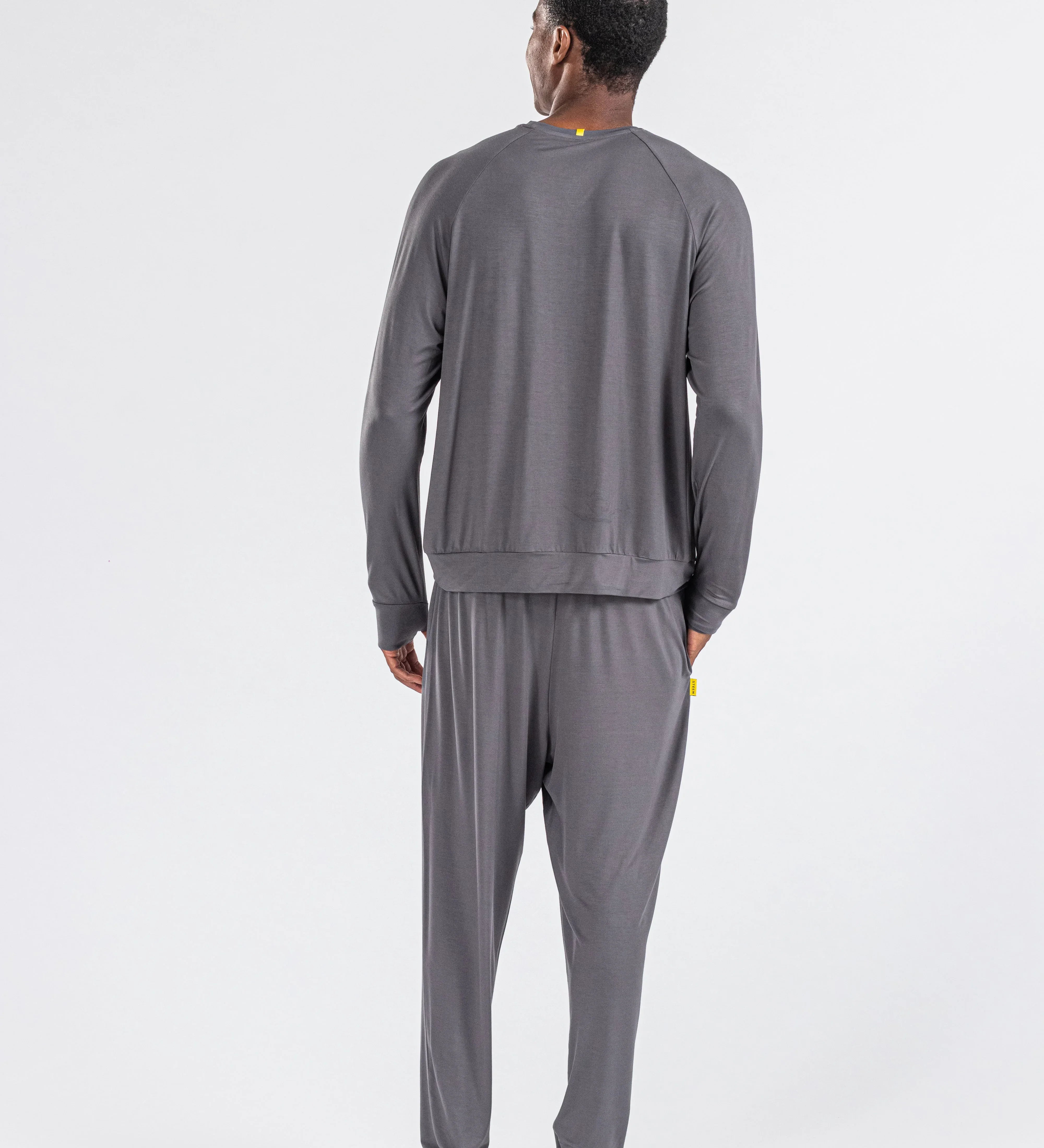 Man wearing charcoal gray loungewear set, long sleeves and pants, standing barefoot