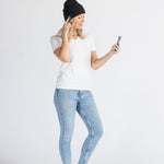 Woman wearing a black music beanie and jeans using smartphone on white background