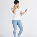 Woman wearing a black music beanie and jeans using smartphone on white background