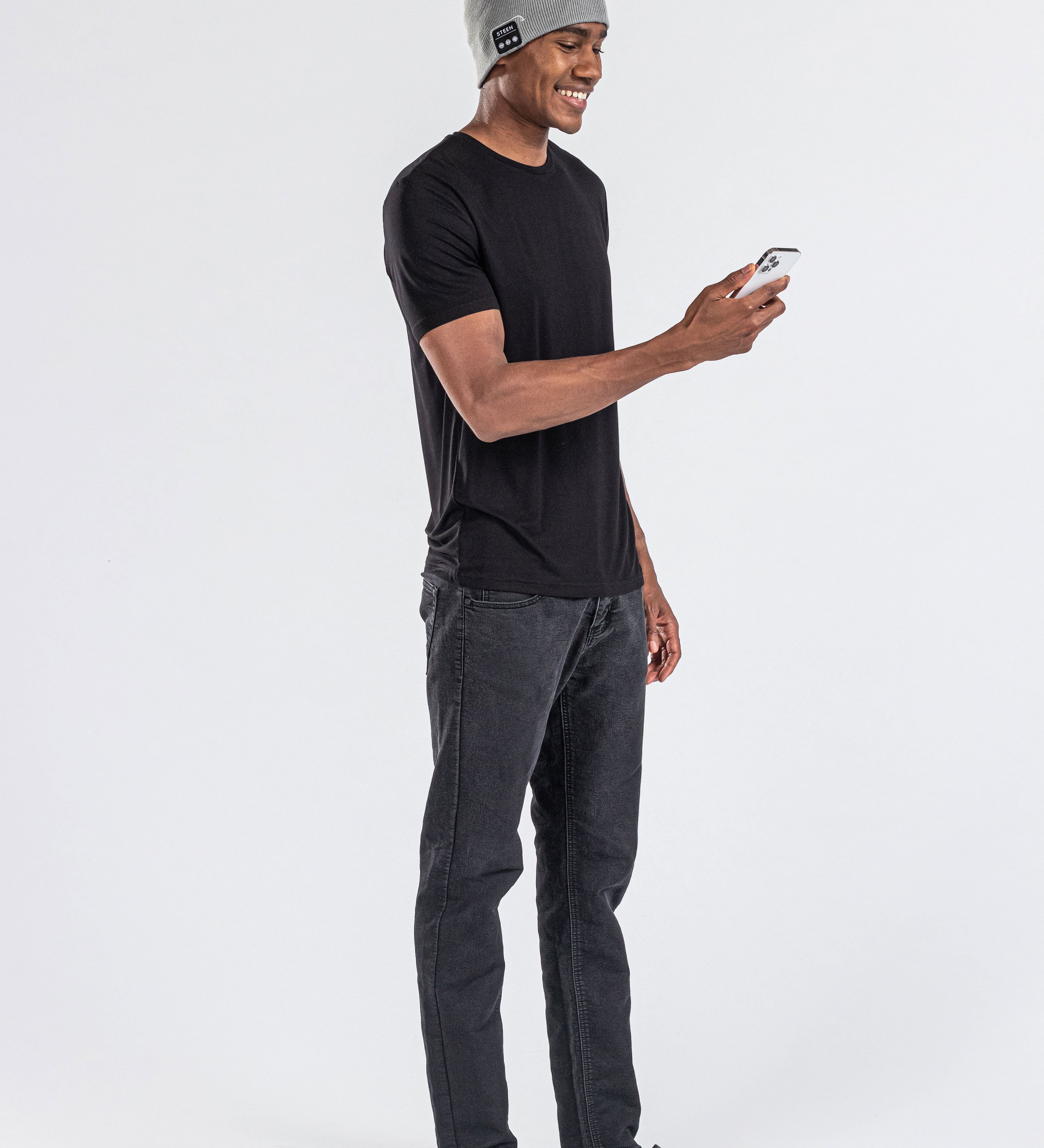 Man wearing grey music beanie with control panel, black t-shirt, using a smartphone
