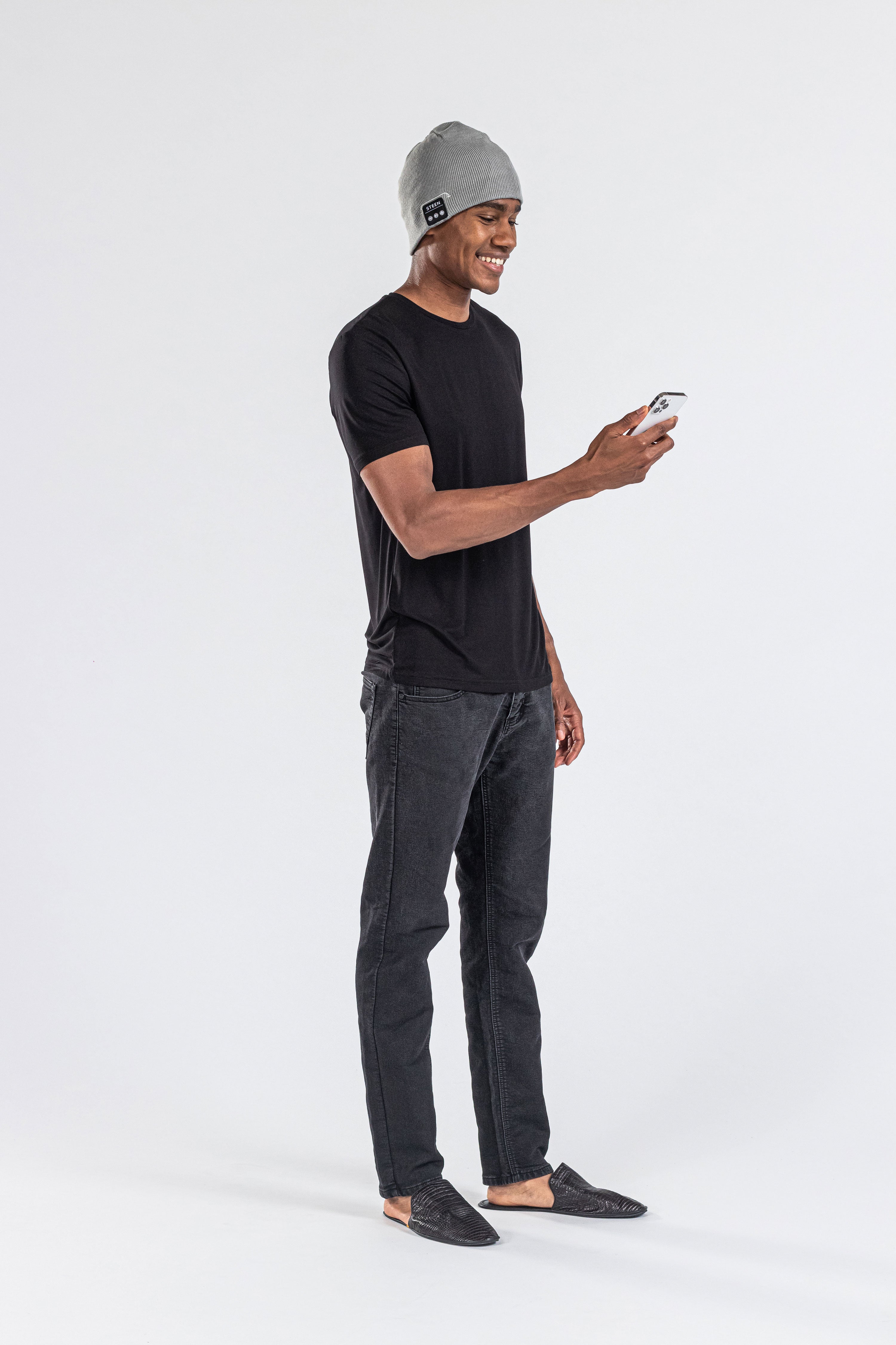 Man wearing grey music beanie with control panel, black t-shirt, using a smartphone