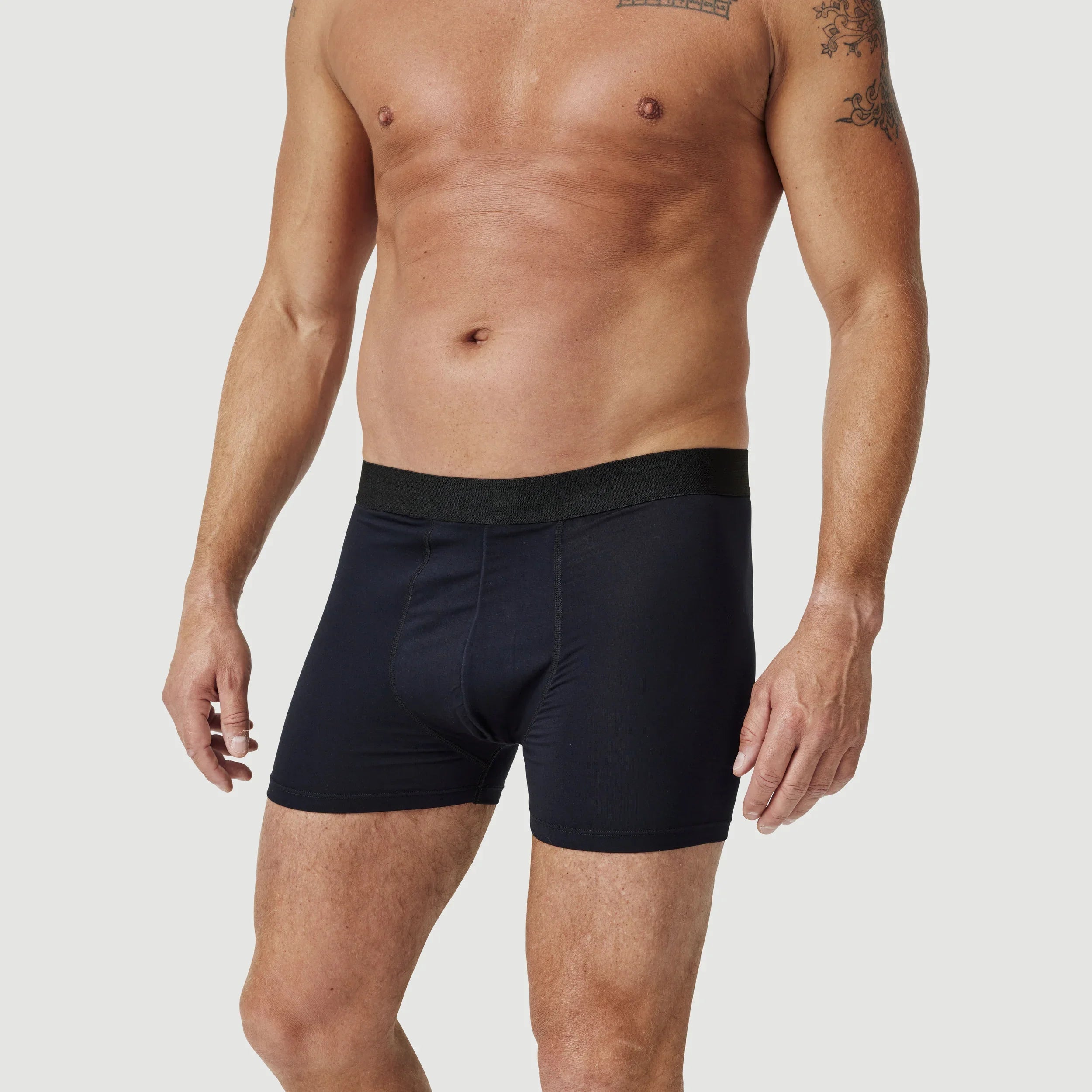 Man modeling black boxer briefs against a plain background for men's underwear fashion