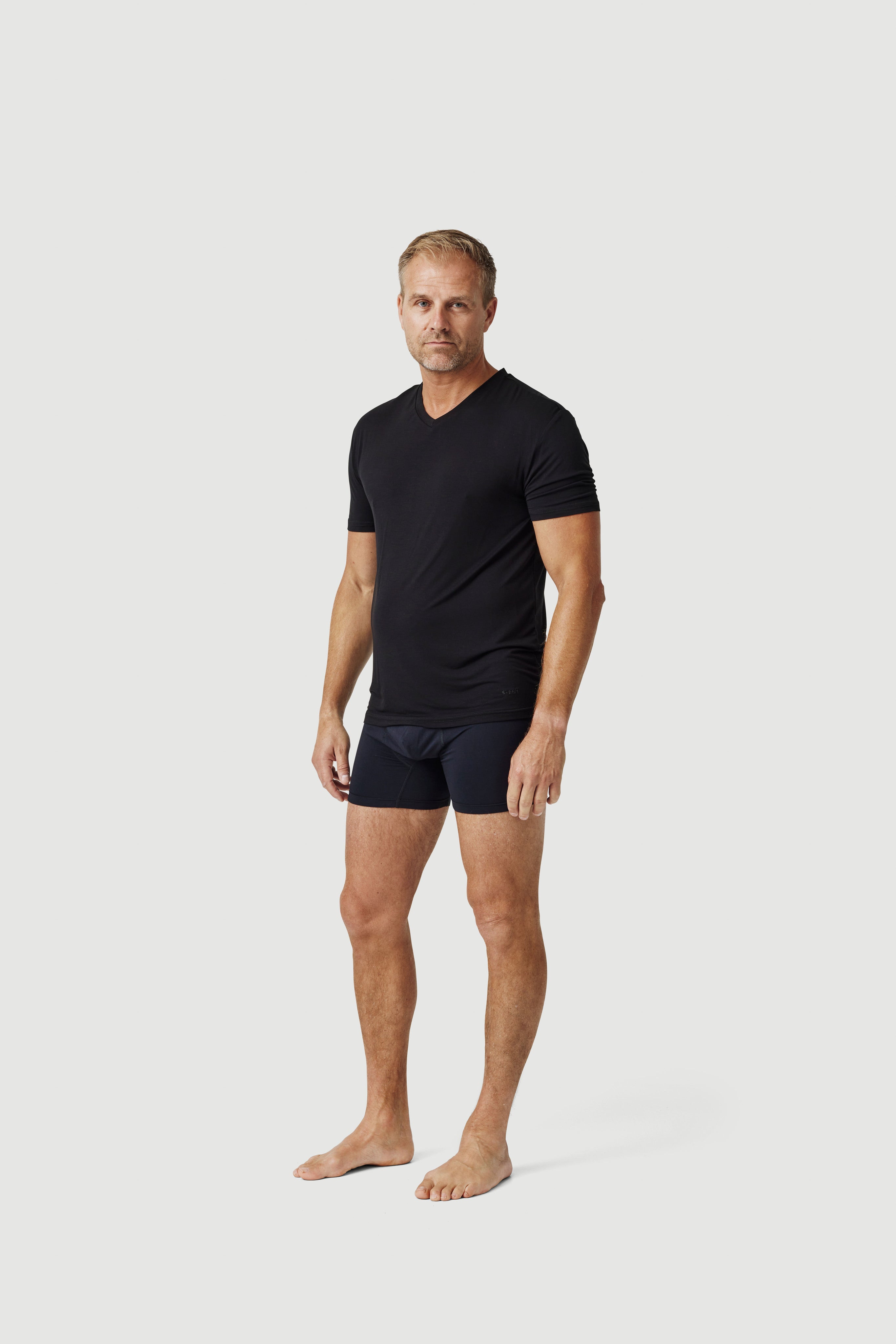 Man modeling black V-neck t-shirt and black boxer briefs on white background