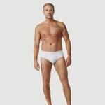 Tattooed man modeling white briefs underwear on plain white background