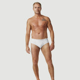 Tattooed man modeling white briefs underwear on plain white background