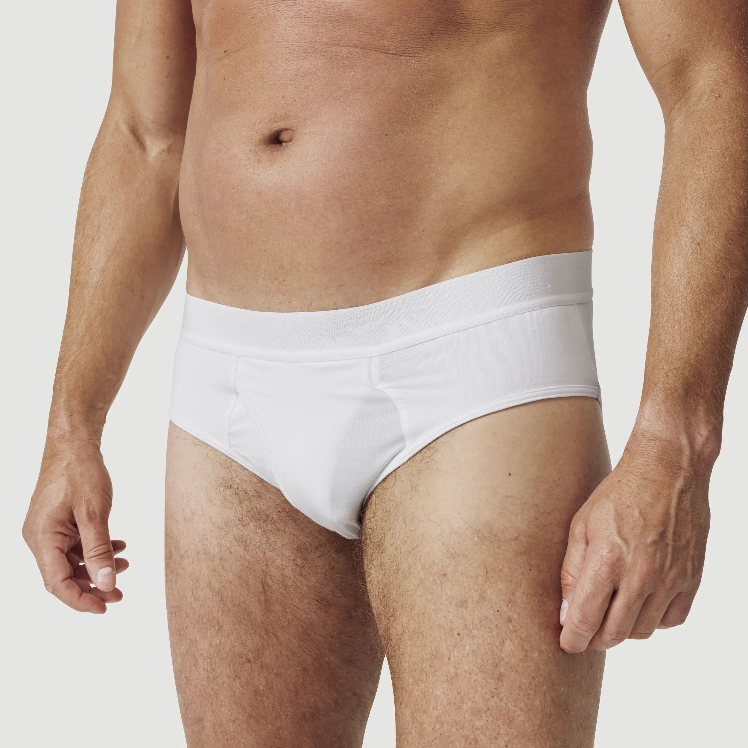 Man wearing white cotton briefs, front view, with neutral background