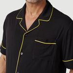 Man wearing black short sleeve shirt with yellow piping and chest pocket