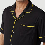 Man wearing black short sleeve shirt with yellow piping and chest pocket