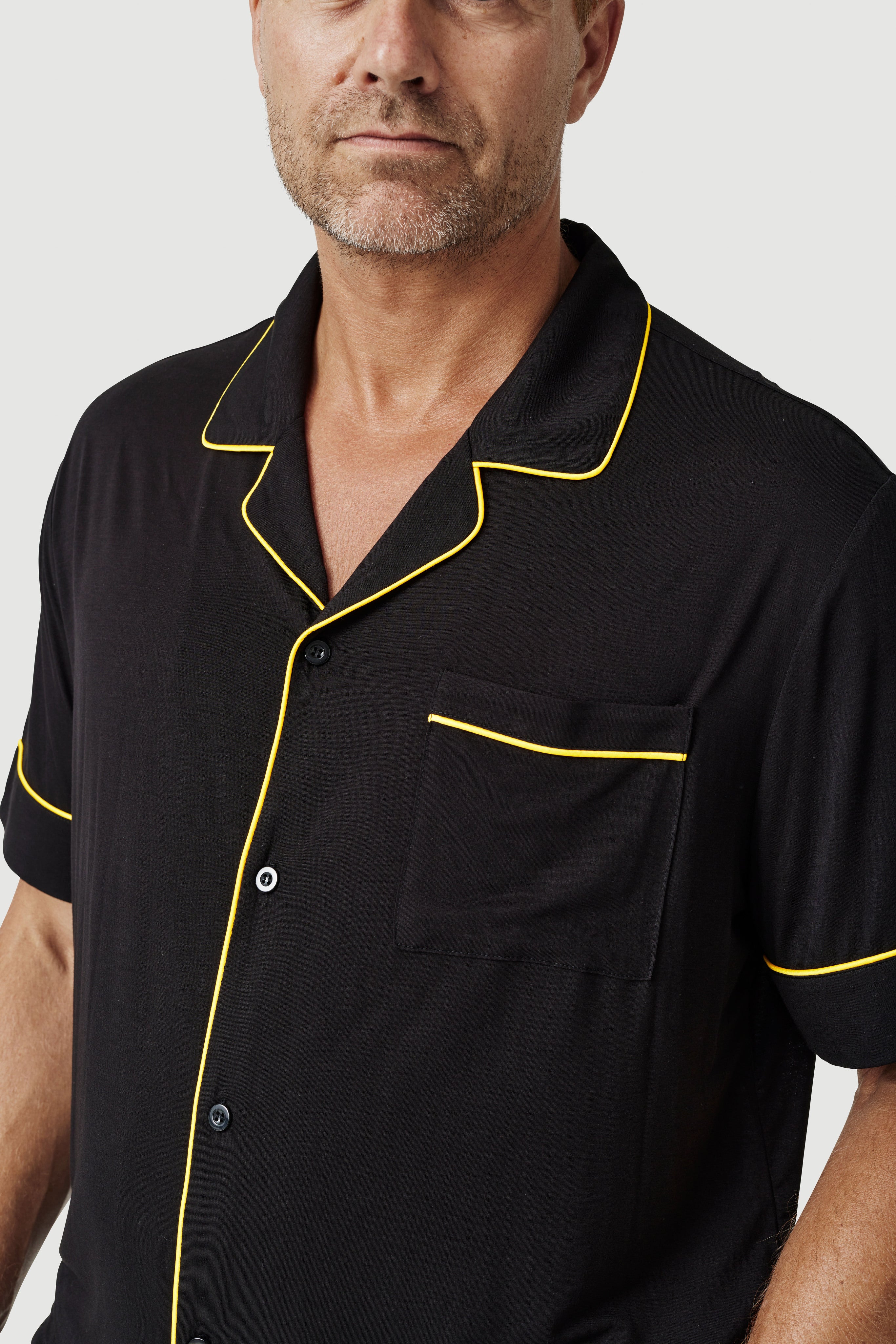 Man wearing black short sleeve shirt with yellow piping and chest pocket