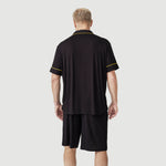 Man wearing black short-sleeve lounge set with yellow trim, back view on light background