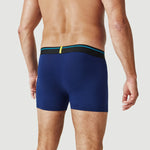 Man wearing navy blue boxer briefs with black waistband, rear view, against light background