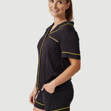 Woman wearing black pajama shorts set with yellow piping, posing against white background