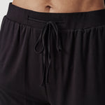 Black athletic shorts with yellow trim and drawstring waistband on model torso