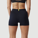 Woman wearing high-waisted black shorts, back view, with yellow accent waistband