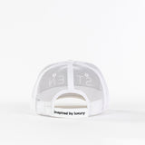 White mesh trucker hat back view with 'inspired by luxury' text on strap