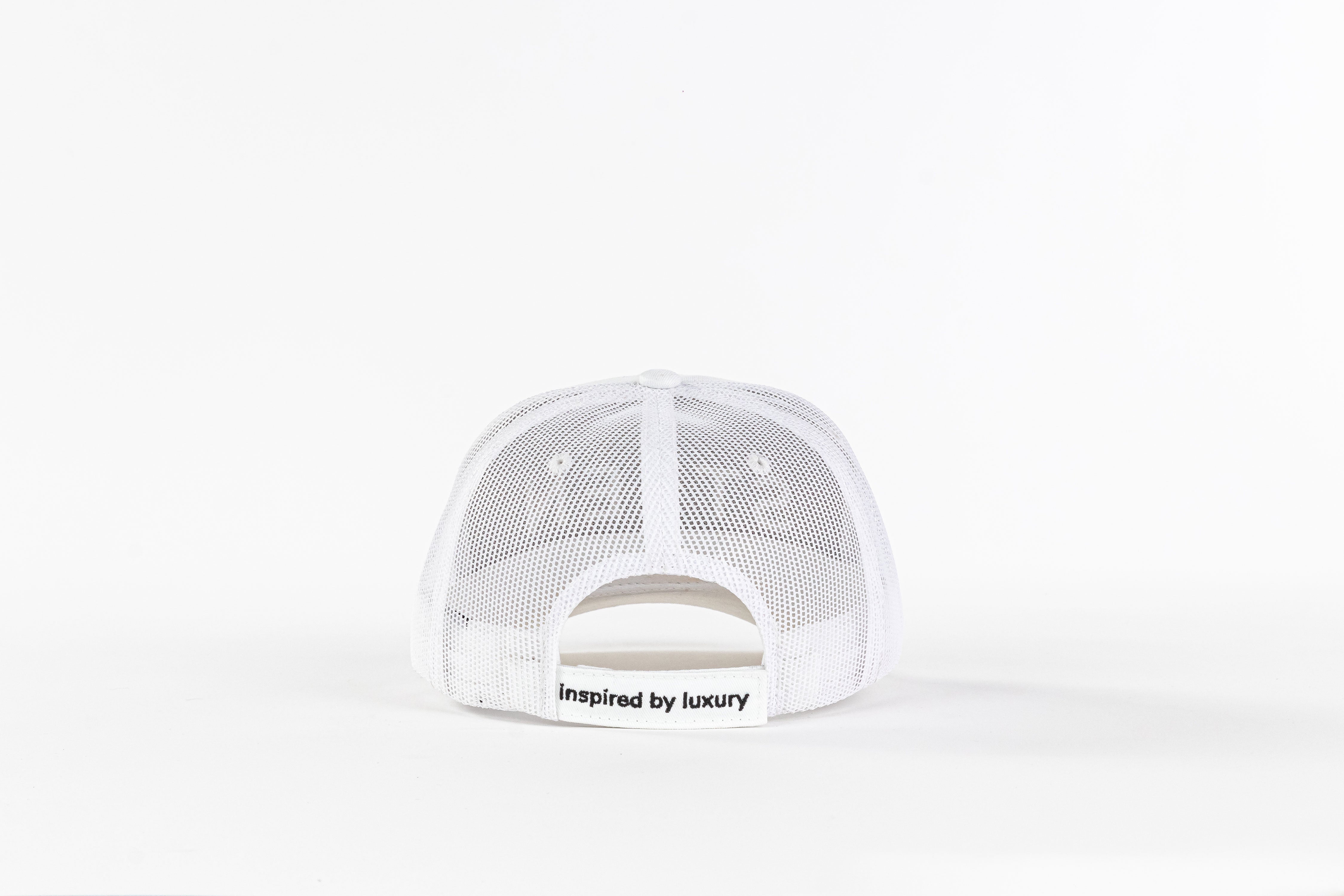 White mesh trucker hat back view with 'inspired by luxury' text on strap