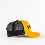 Yellow and black mesh trucker hat with embroidered ST letters on plain white background
