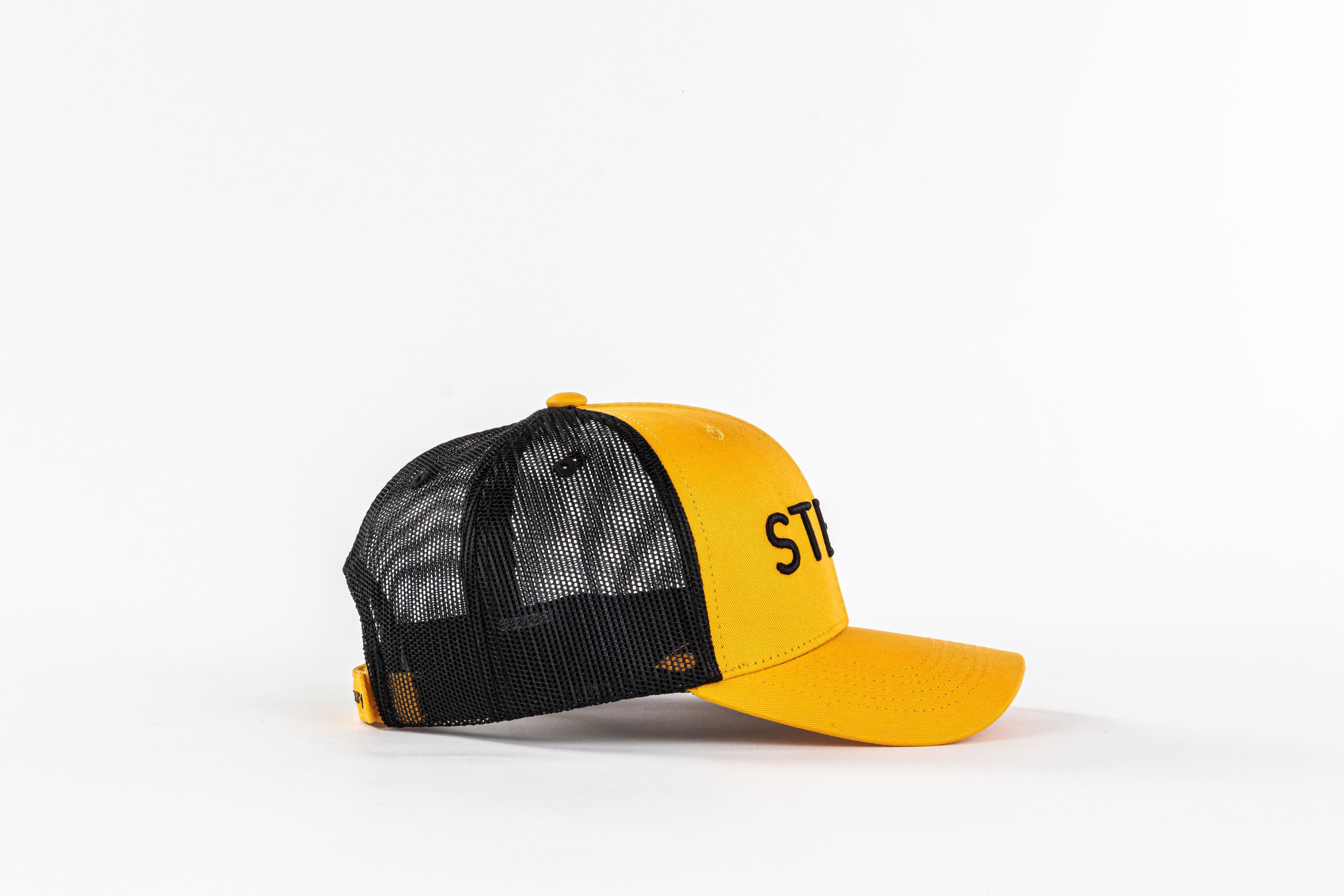Yellow and black mesh trucker hat with embroidered ST letters on plain white background