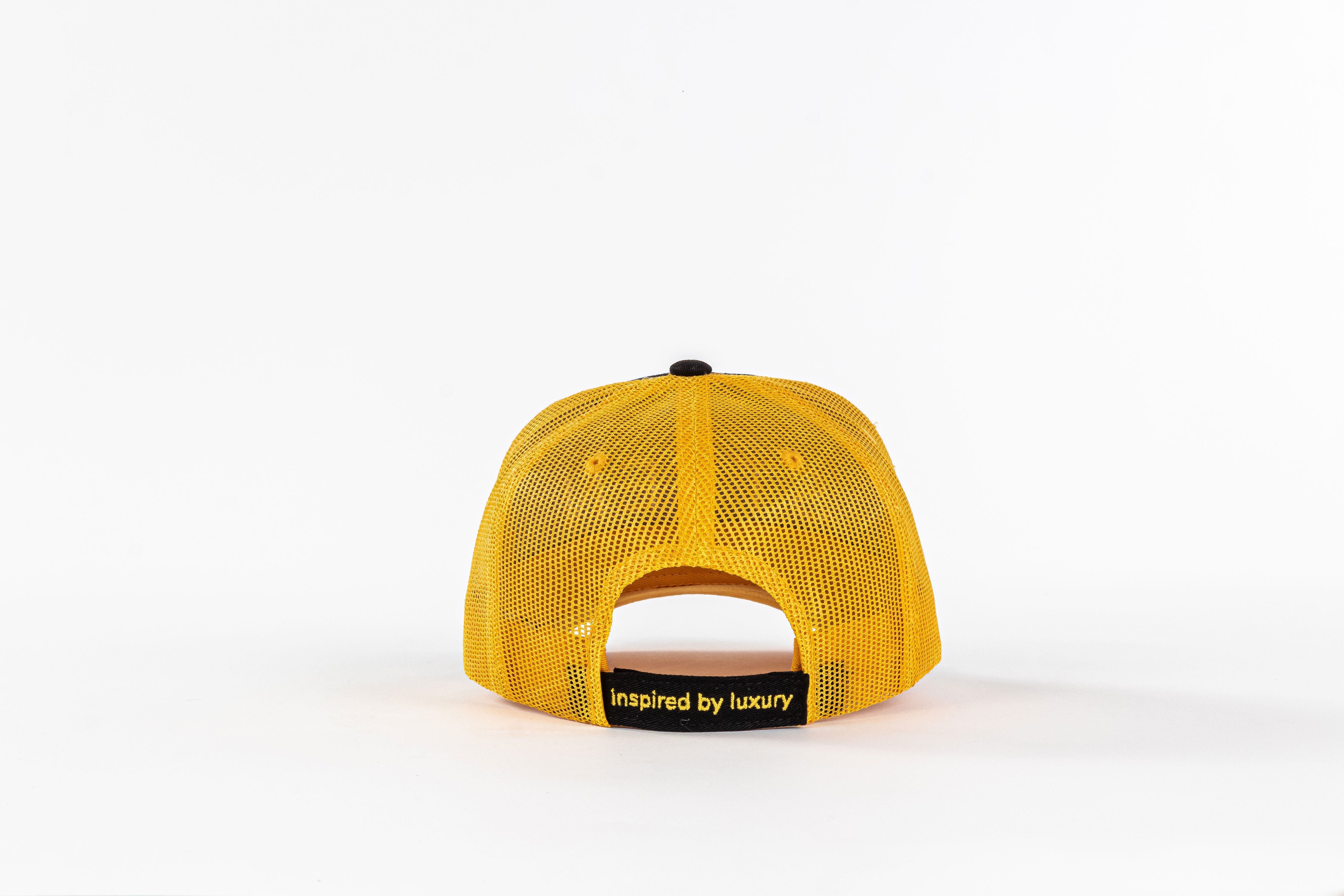 Yellow mesh trucker hat back view with 'inspired by luxury' text on black strap