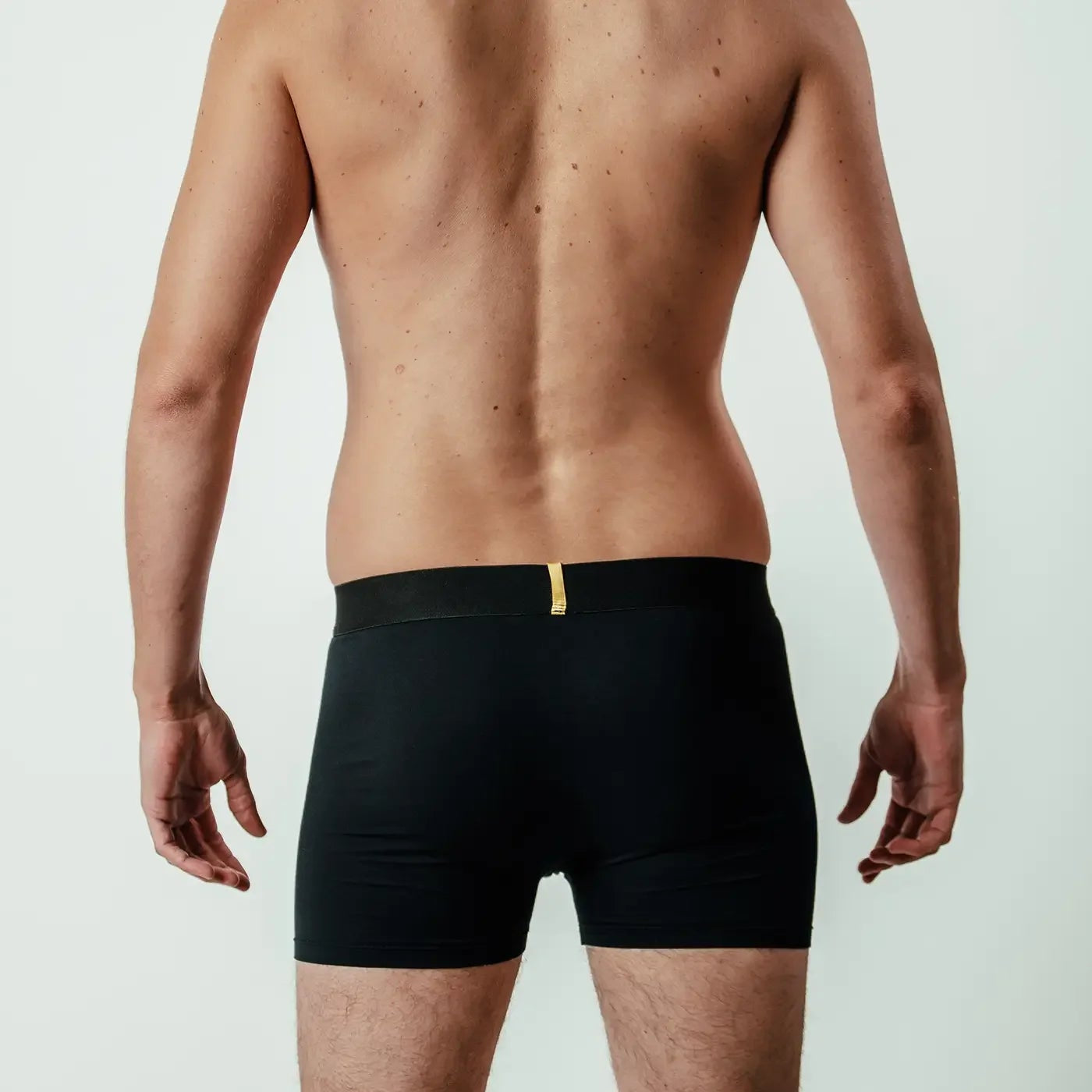 Back view of man wearing black Steen bamboo boxer briefs with gold waistband detail