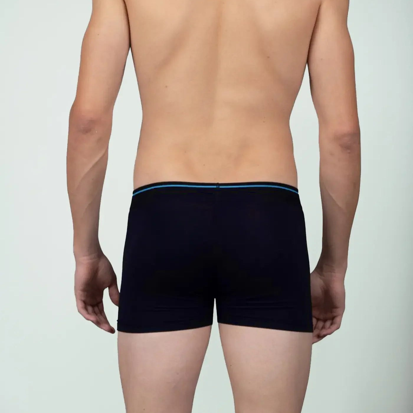 Back view of man wearing blue bamboo boxer briefs against plain background