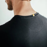 Close-up of man wearing black shirt with yellow tag on neckline, back view