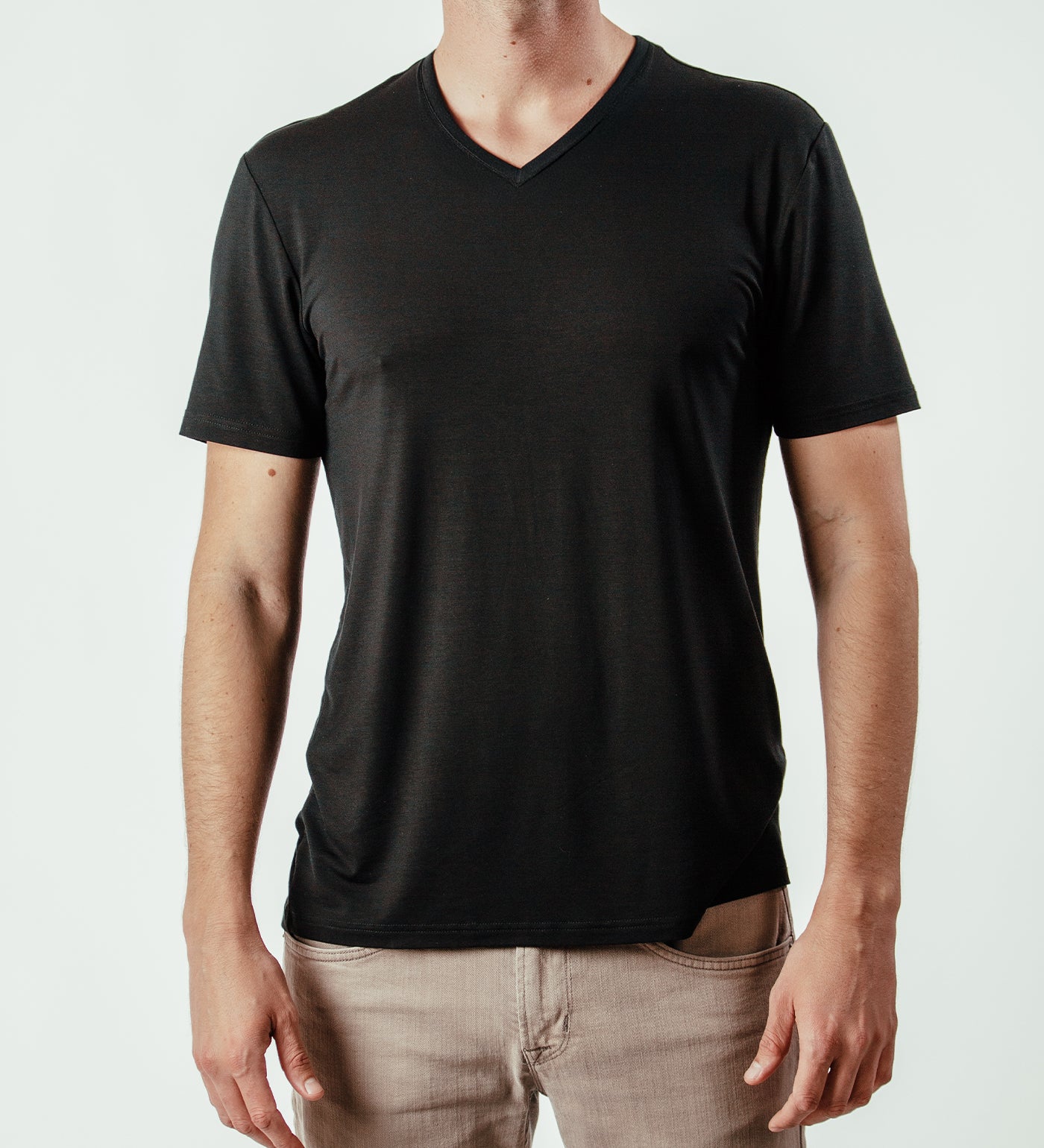 Man wearing plain black V-neck T-shirt and beige jeans, front view, isolated background