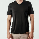 Man wearing plain black V-neck T-shirt and beige jeans, front view, isolated background