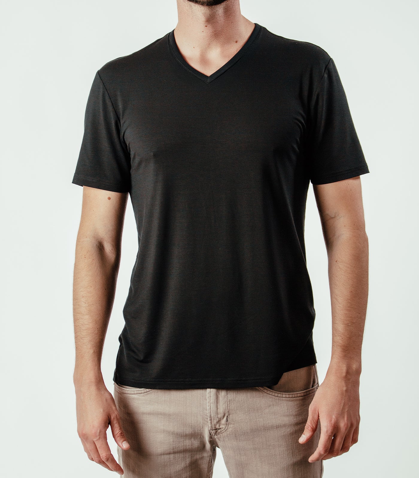 Man wearing plain black V-neck T-shirt and beige jeans, front view, isolated background