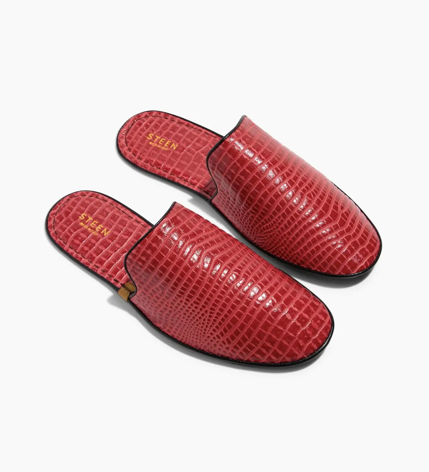 Red women's slippers with crocodile pattern and black trim on white background